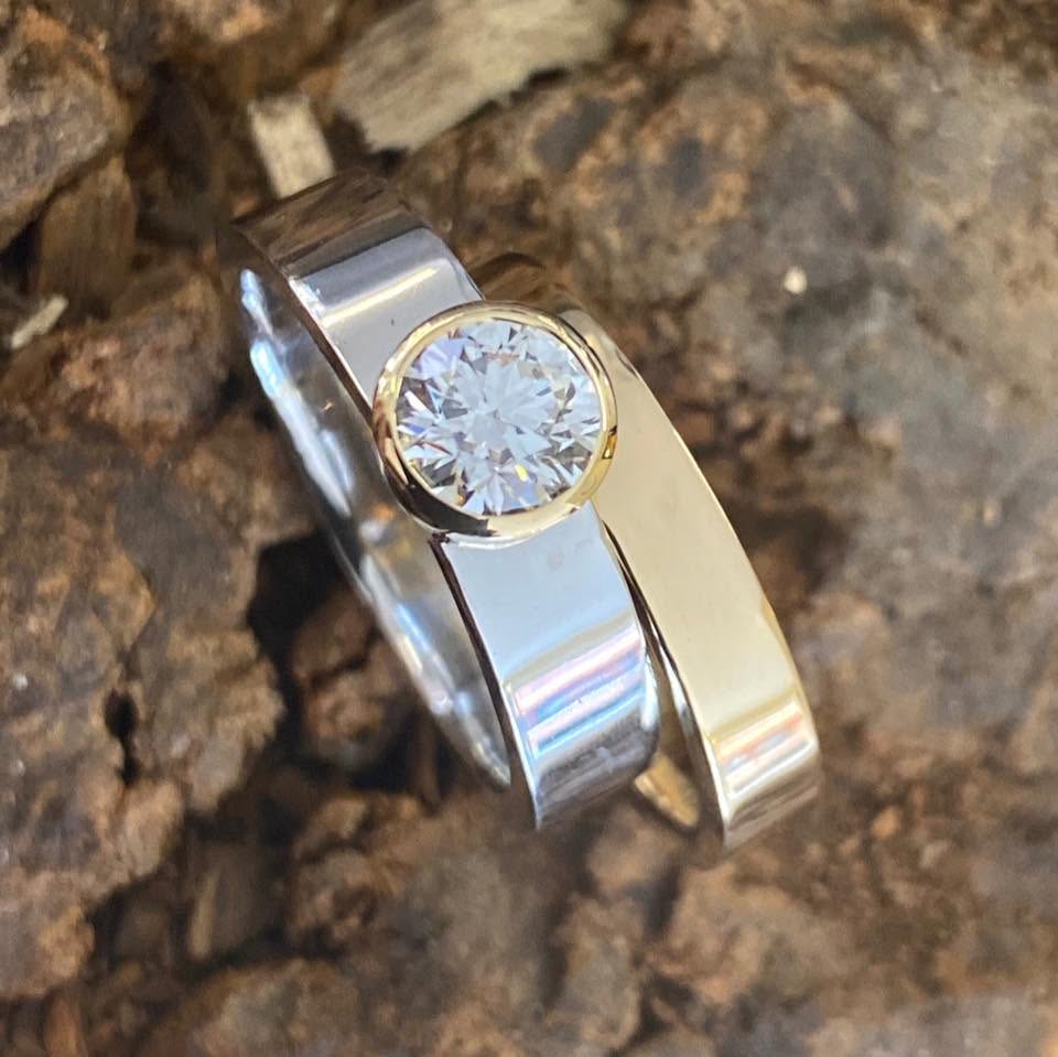 Two-tone ring with a round clear centre stone on textured bark